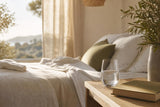 Dormitorio luminoso con un vaso de agua junto a la cama al amanecer