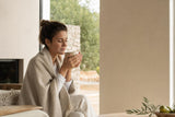 Mujer con una taza templada cuidando la irritación de garganta en casa