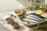 Pescado azul, nueces y semillas en una mesa de cocina mediterránea.