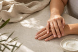 Manos con uñas naturales cuidadas sobre una superficie clara