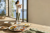 Desayuno mediterráneo con alimentos fuente de vitamina D junto a una ventana luminosa.